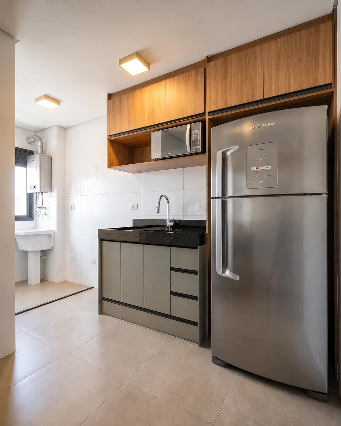 Cozinha do projeto Pico Negro, apartamento para investimento em São Paulo, com marcenaria amadeirada e bancada em granito preto